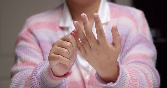 Close-up of an individual pinching her fingers one by one, massaging herself to relive the pain and inflammation she is feeling.