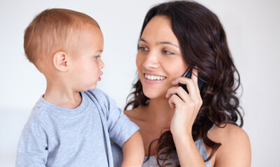 Mom holding toddler in home with phone call, smile and child care with support in morning. Happy woman, baby boy and bonding together in bedroom with chat on cellphone, multitasking and mothers love.