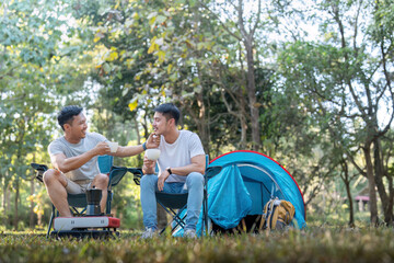 Male gay couple asian traveling with tent camping outdoor and various adventure lifestyle hiking active summer vacation. drinking coffee and talking together