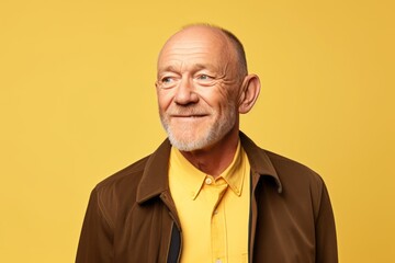 Portrait of a happy senior man looking at camera on yellow background