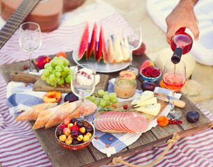 Man pouring wine having picnic on beach