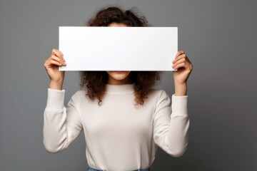 young african american woman covering face with blank sheet of paper