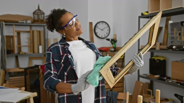 African american woman artist examining wooden picture frame in a well-organized carpentry workshop