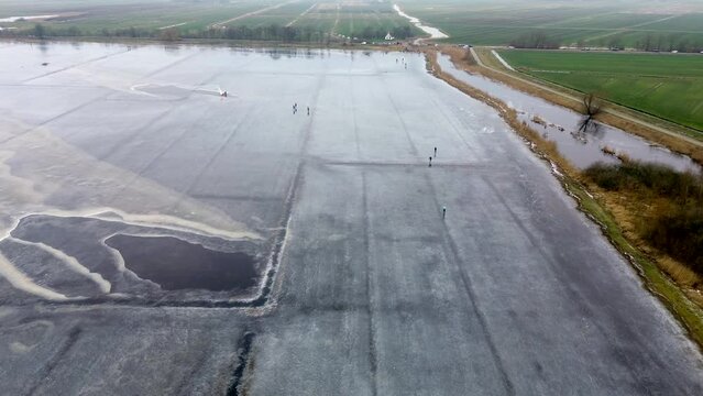 High quality aerial drone footage of people ice skating on a frozen lake in winter near Sneek, Friesland, the Netherlands