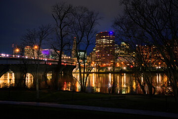 Fototapeta na wymiar Hartford Skyline behind bare tree branches at night over the Connecticut River, USA