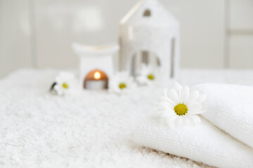Obraz na płótnie Canvas White towels with chamomile flower and aroma lamp, candle. Spa and wellness or beauty salon, romantic relaxation concept. Copy space. Womens Day. Valentines Day.