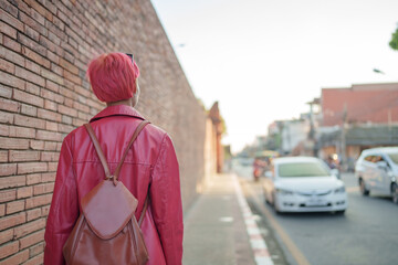 Gen z girl leather fashion with punk Asian woman tourist of local city Southeast Asia travel trendy pink hairstyle young female punk traveler walking around in town