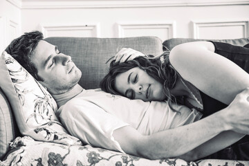 Young couple liying on the sofa in their flat, before sex and making love, and sleeping, taking a...