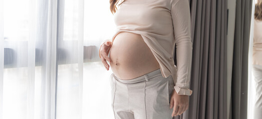 Pregnant woman holds hands on belly touching her baby caring about her health Beautiful happy...