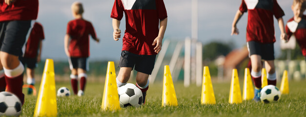 Professional Soccer Coaching. Soccer Drills in Dribbling Ball Between Practice Cones. Young Players Kicking Balls and Improving Ball Mastery Skills. Football Academy For School Children