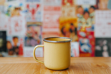 Chocolate drink with powder on yellow enamel mug with bokeh background