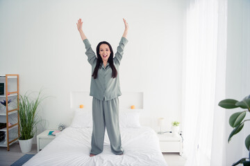 Photo portrait of lovely young lady raise hands stand bed dressed stylish gray sleepwear isolated...