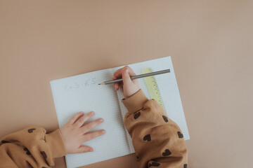 Kind schreibt Rechenaufgabe in Schulheft