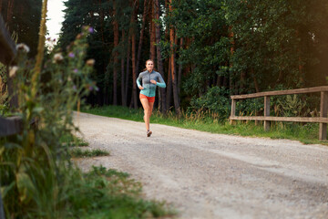 Fototapeta na wymiar Mid adult woman running on forest road during summer afternoon