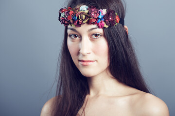 Woman, portrait and flower headband in hair with beauty, skin glow and wellness on grey background. Face, hairstyle with floral head gear or accessory, dermatology and cosmetics to blossom in studio