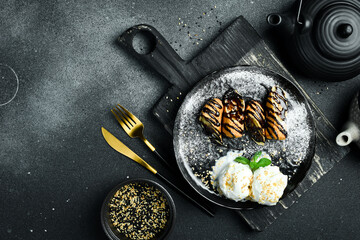 Ice cream balls and pieces of banana with chocolate on a plate. Sweet dessert.