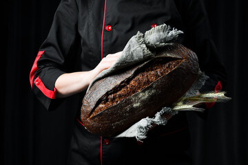 Fragrant black oval bread in female hands. Homemade rye bread.