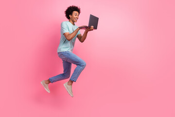 Full length photo of handsome young male running hold netbook hurry wear trendy blue garment isolated on pink color background
