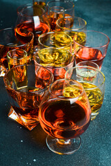 A set of glasses with different alcoholic beverages: rum, tequila, whiskey or brandy, cognac and vodka, on a stone table. Strong aged alcoholic drinks. On a stone background.