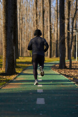 Athlete running in the park, view from back