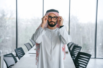 Young investor is standing. Successful Muslim businessman in traditional outfit in his office