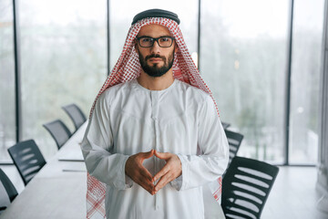 In glasses. Successful Muslim businessman in traditional outfit in his office