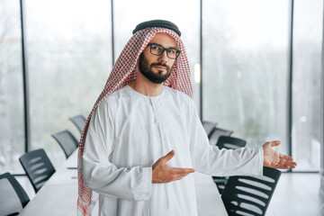 In glasses. Successful Muslim businessman in traditional outfit in his office