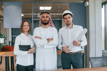 Standing together. Muslim businessman in traditional outfit with colleagues in office