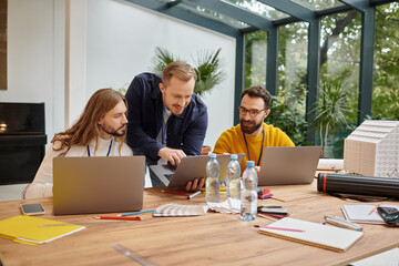 joyous attractive businessmen in casual attire working attentively on their startup together