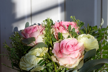 Nahaufnahme von einem Pastell Blumenstrauß von weißen und rosa Rosen angeleuchtet von der Winter...