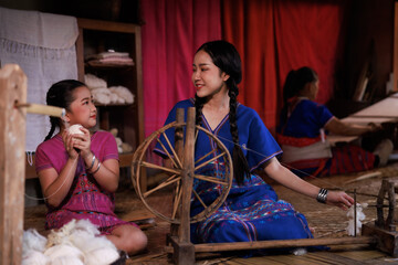 mother and daughter help each other spin yarn with traditional equipment,