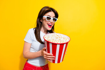 Portrait of ecstatic girl wear t-shirt in 3d glasses hold popcorn look at promotion empty space...