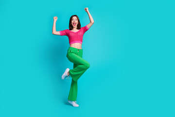 Full size photo of overjoyed girl wear pink knit top green trousers raising hands up yell win...
