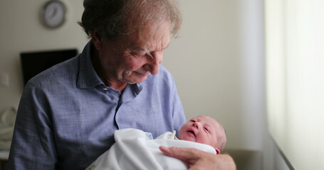 Newborn baby infant being grand-father next to hospital window