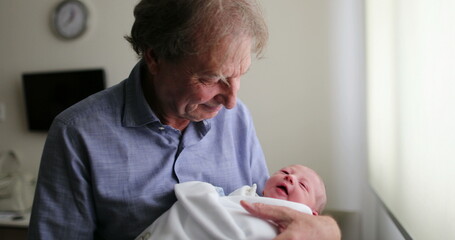 Newborn baby infant being grand-father next to hospital window