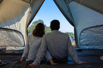 back view caucasian couple sitting inside a tent on camping trip,