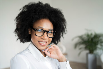 Stylish young woman in glasses smiling, conveying confidence and positivity.