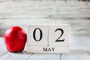 White wood calendar blocks with the date May 2nd and a red apple for National Teacher Appreciation Day. 