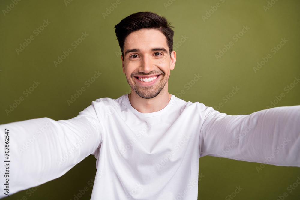 Sticker Self portrait of optimistic brunet hair young businessman holding camera and shooting his life blog isolated over khaki color background