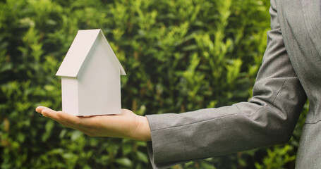 Selling or buying a home - hand holding a paper house - 707863779