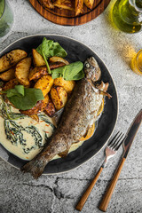 Portion of cooked grilled fish with potato and sauce