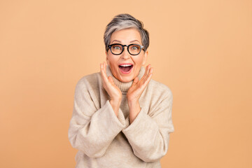 Photo of impressed speechless grandmother raise arms open mouth news reaction isolated on beige...