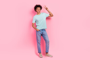 Full length photo of handsome young male showing v-sign promo dressed stylish blue garment isolated on pink color background