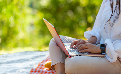 Young woman using laptop personal computer outdoors natural park, online working, freelancer...