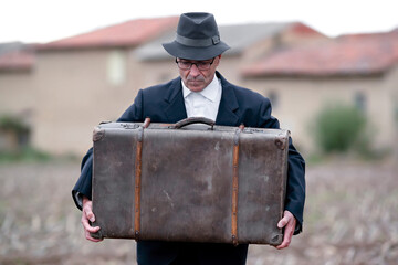 emigrant with suitcase and vintage suit leaving his village to look for work at early 20th century...