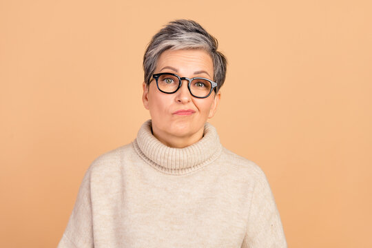 Photo of unsatisfied pensive aged lady sullen face disappointment doubts isolated on beige color background