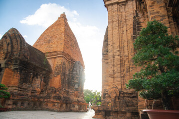 Unidentified tourists walking along narrow space between North Tower or Thap Chinh and Central Tower or Thap Nam of Ponagar Cham Towers, terraced pyramidal roof, built partly recycled bricks