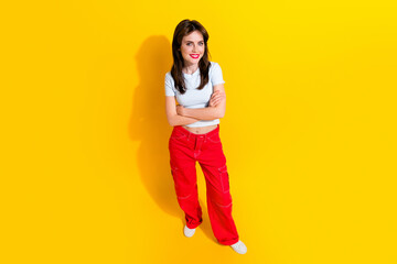 Fototapeta na wymiar Full length top view photo of cool confident lady wear white t-shirt smiling arms folded isolated yellow color background