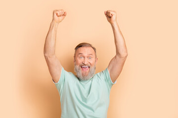 Photo of overjoyed cheerful senior man dressed trendy clothes raise hands yell yeah isolated on...