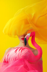 노란 배경에 핑크 플라밍고를 들고있는 여자